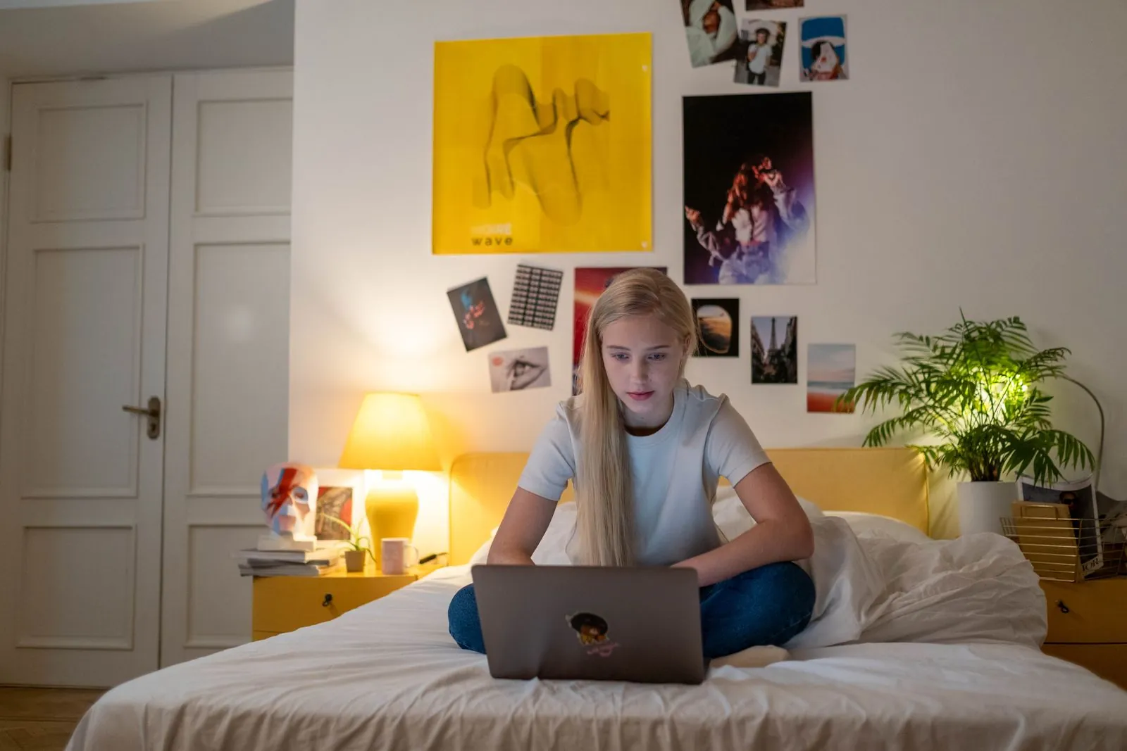 Adolescente rubia con un portátil sobre la cama de su habitación